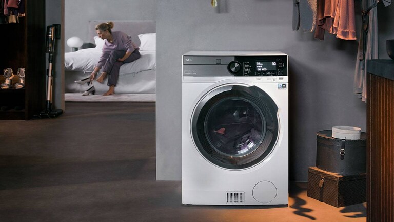 Egy nő egy AEG mosó-szárító gépnek dőlt