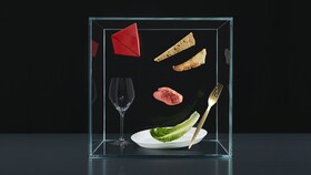 A Taking Taste Further élményelemeit bemutató evőeszközök, tányérok és alapanyagok egy üvegdobozban.