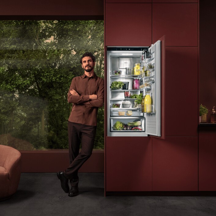 Man standing next to a fridge in a kitchen.